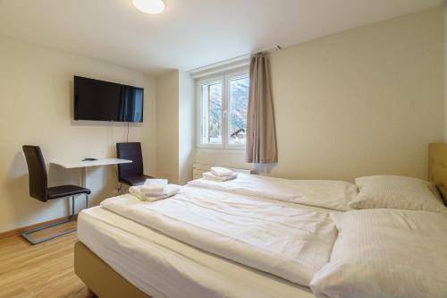 a large white bed in a room with a window at Haus Astoria in Saas-Grund