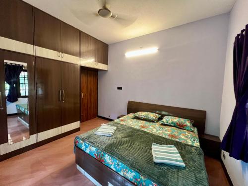 a bedroom with a bed with a green comforter and wooden cabinets at Zeno Villa Malpe - Premium Villa in Malpe
