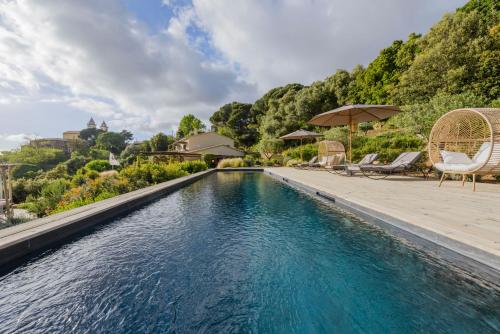 - une piscine à débordement avec des chaises et des parasols à côté d'une maison dans l'établissement Terre de Maquis, maison d'hôtes vue mer Corse, à Sari-dʼOrcino
