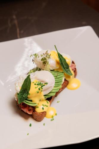 a sandwich with eggs and greens on a white plate at Boutique Hotel Whisky in Tirana