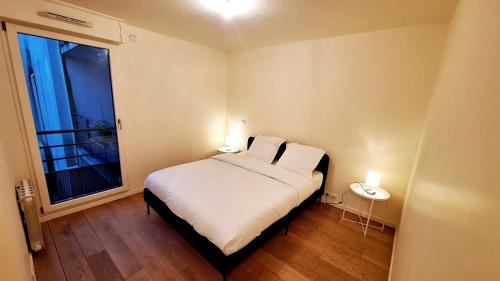 une chambre avec un grand lit blanc avec deux lampes dans l'établissement Appart cosy tout confort Metro 11 avec parking, à Paris