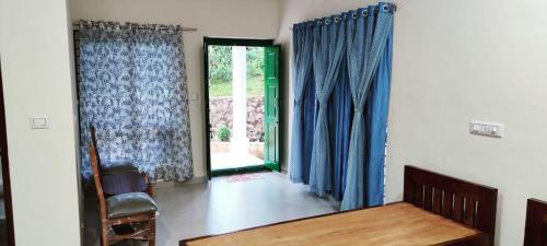 a living room with blue curtains and a door at Malnad Bliss in Sringeri