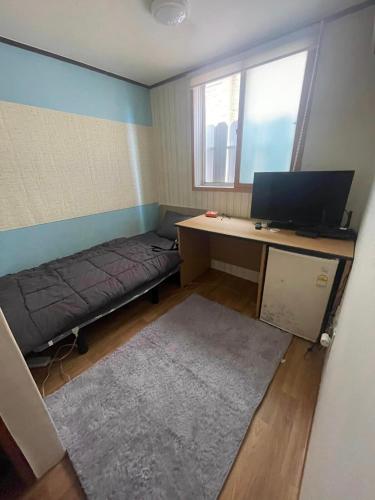 a room with a desk with a computer and a couch at GwangJu SunFlower Hostel in Gwangju