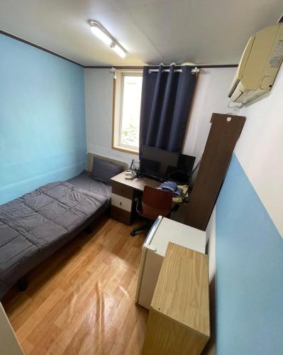 a bedroom with a bed and a desk with a computer at GwangJu SunFlower Hostel in Gwangju