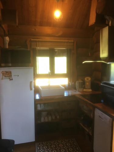 une cuisine avec un évier blanc et une fenêtre dans l'établissement Un Chalet en Corrèze, à Auriac
