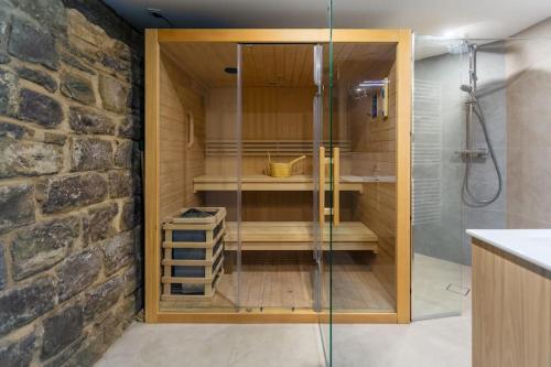 La salle de bains est pourvue d'une douche en verre et d'un mur en pierre. dans l'établissement Maison rénovée Climatisée avec Sauna et Baby-Foot, à Strasbourg