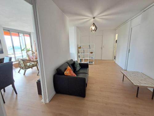un salon avec un canapé noir et une table dans l'établissement Appartement T4 Lyon 9, à Lyon