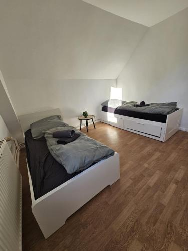 two beds in a white bedroom with a wooden floor at Modernes Wohlfühl Apartment in Schwanewede