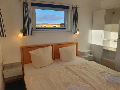 a bed with two pillows in a bedroom with a window at FLOATING HOUSES - "schwimmende Ferienhäuser" - Haus 2 in Kröslin
