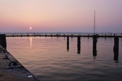 a pier in the water with the sunset in the background at Ferienwohnung Irmchen in Altefähr