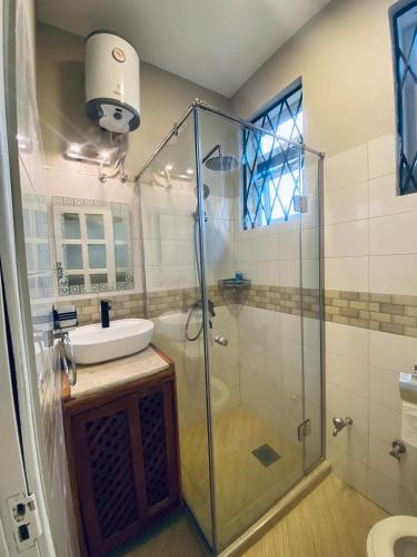 a bathroom with a glass shower and a sink at Jacomo Residences in Dar es Salaam