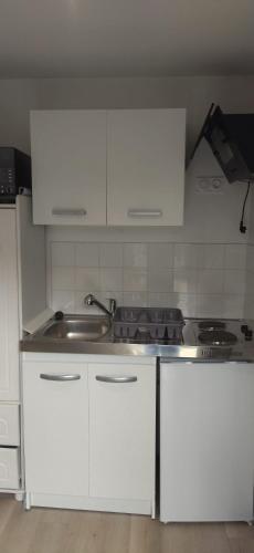 une cuisine avec des armoires blanches et un évier dans l'établissement Studio plein de charme, à Les Sables-dʼOlonne