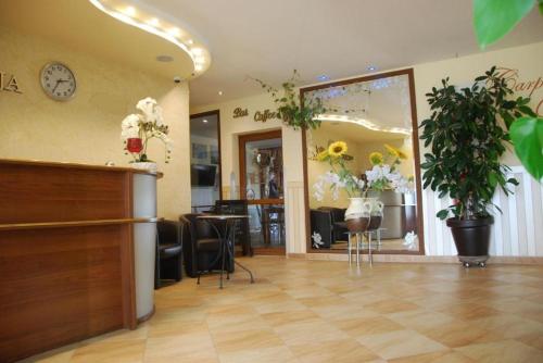 a salon with a waiting area with a clock and flowers at Noclegi Kochlice in Kochlice