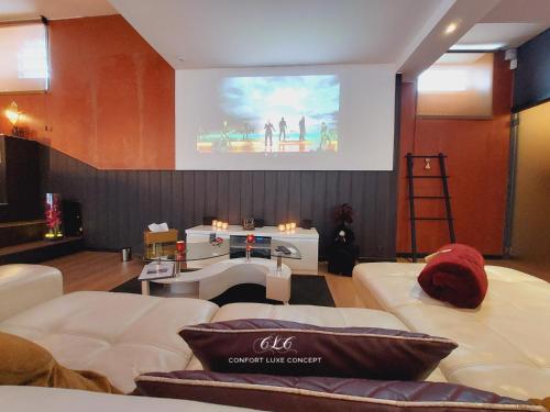 a living room with two white couches and a large screen at Le BELLEA in Verviers