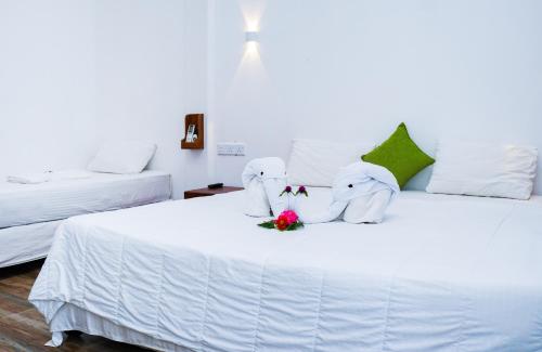 two stuffed elephants are sitting on a white bed at Dinuda Resort in Kalpitiya