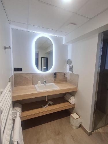 une salle de bain avec un lavabo et un miroir dans l'établissement Hôtel Breizh Du Golfe, à Arzon