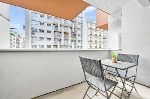 d'une petite table et de chaises sur un balcon avec une grande fenêtre. dans l'établissement La Felicita - Studio avec Balcon Paris - Netflix, à Paris