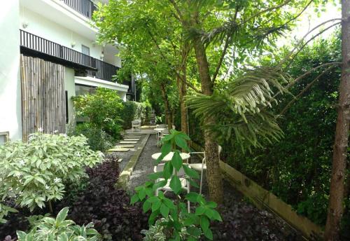a garden with trees and plants in front of a building at Collection O The Singha Chiangmai Hotel in Chiang Mai