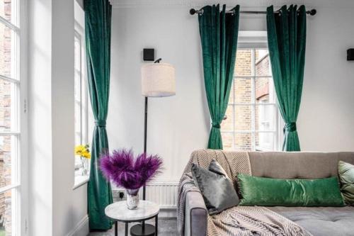 a living room with green curtains and a couch at Liverpool street Apartment in London