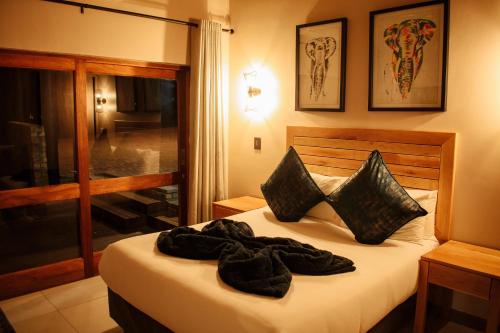 a bedroom with a bed with black sheets and pillows at DUBE SAFARI LODGE at Kruger Park Lodge 505 in Hazyview