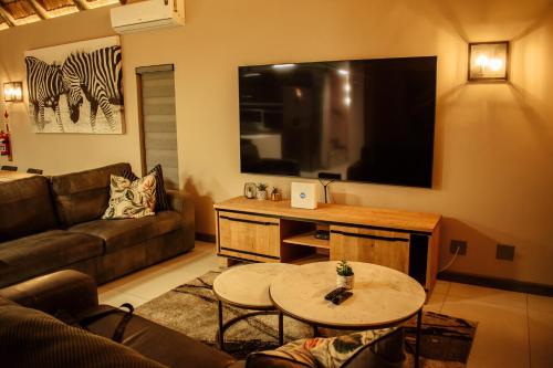 a living room with a couch and a flat screen tv at DUBE SAFARI LODGE at Kruger Park Lodge 505 in Hazyview