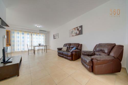 a living room with two leather couches and a television at Cosy 2BR penthouse with private balcony by 360 Estates in Siġġiewi