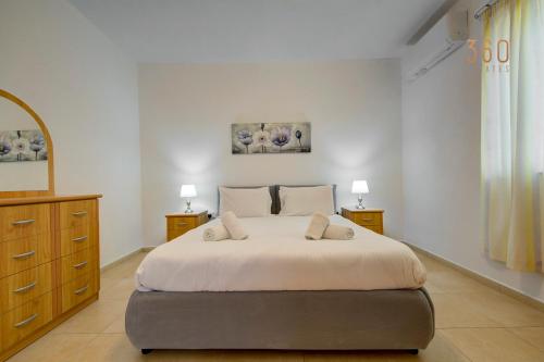 a bedroom with a large bed with two night stands and two lamps at Cosy 2BR penthouse with private balcony by 360 Estates in Siġġiewi