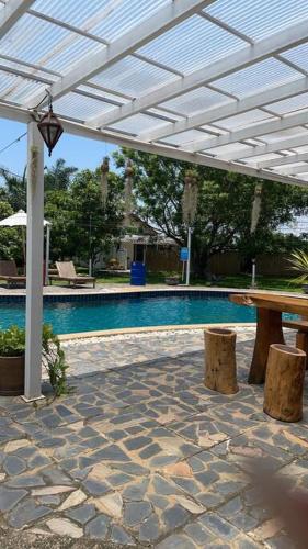 a swimming pool with a white pergola and a table and benches at บ้านพักริมทุ่งนา in Ban Muang Len