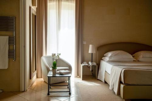 a bedroom with a bed and a chair and a table at La Fiermontina Luxury Home Hotel in Lecce