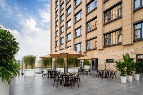 an outdoor patio with tables and chairs in front of a building at Holiday Inn Express Chengdu Huanhuaxi by IHG-Near Jinsha Site Musem,Near Wuhou Temple Museum,Welcome drinks,Free gym,Free self-service laundry in Chengdu
