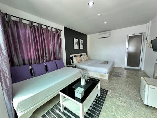 a room with two beds and a table in it at บ้านชวนชมเกาะล้าน in Ko Sak