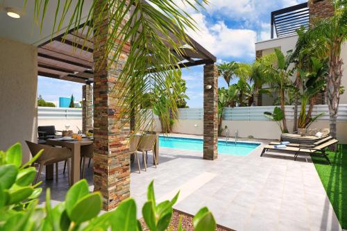 a patio with a table and chairs and a swimming pool at Villa Anastasia - Fig Tree Bay Area in Protaras