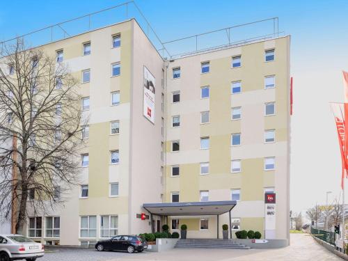 a large white building with a car parked in front at ibis Stuttgart Airport Messe in Leinfelden-Echterdingen