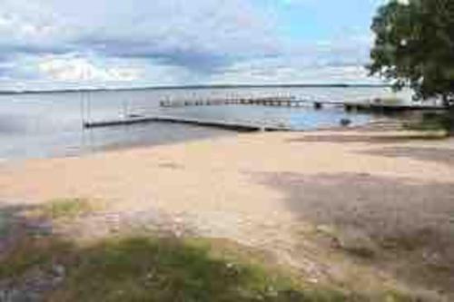 a beach with a dock in the water at Nybyggt -med spabad, bastu och nära stor badstrand in Kungsör