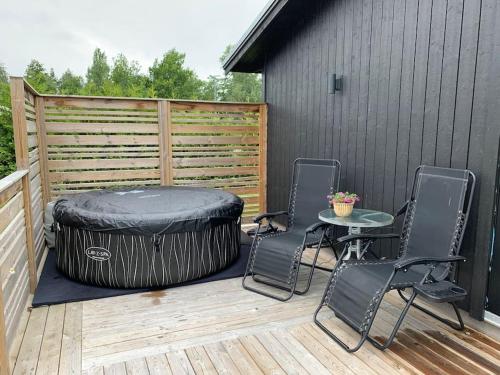 a patio with a table and chairs on a wooden deck at Nybyggt -med spabad, bastu och nära stor badstrand in Kungsör