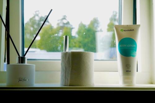 a window sill with three toiletries on a table at Nybyggt -med spabad, bastu och nära stor badstrand in Kungsör
