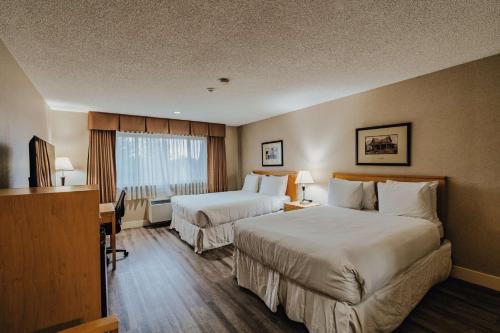 a hotel room with two beds and a desk at SureStay Plus by Best Western Coquitlam in Coquitlam