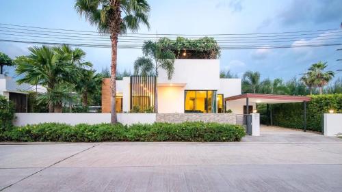 a white house with palm trees in front of it at The Sea-Cret Garden Hua Hin in Hua Hin