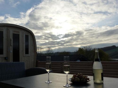 a table with two glasses of wine and a bowl of fruit at Ferienhaus Henneglück3 mit Sauna in Meschede