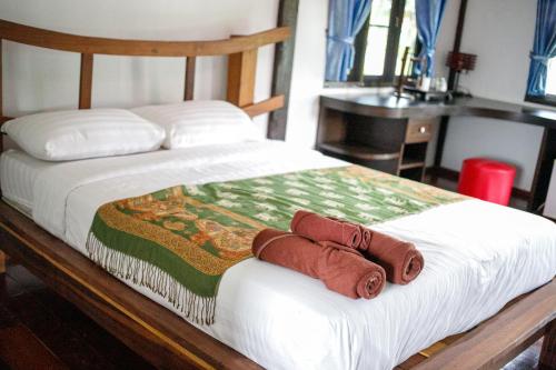 a bed with two towels on top of it at บ้านพักริมทุ่งนา in Ban Muang Len