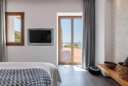 a bedroom with a bed and a tv and a balcony at Mileo in Kalo Livadi