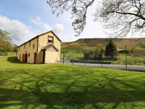 an old building in a field with a grass yard at Ty Hir at Blaenbrynich Farm in Brecon