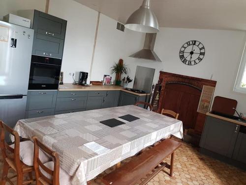 une cuisine avec une table, des chaises et une horloge murale dans l'établissement Maison de Vacances LUCYANN, à Avrillé