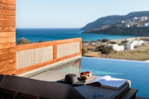 a table with an open book on a balcony with the ocean at Mileo in Kalo Livadi
