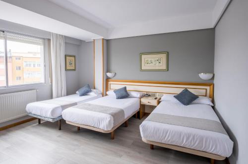 a hotel room with two beds and a window at Hotel Alda Boiro in Boiro