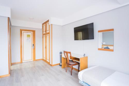 a bedroom with a bed and a desk and a tv at Hotel Alda Boiro in Boiro