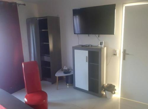 a living room with a red chair and a flat screen tv at Love Room Sensuelle in Tremblay En France
