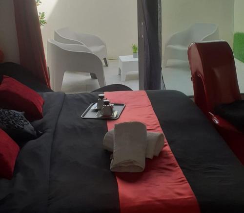 a bed with a red and black blanket with towels on it at Love Room Sensuelle in Tremblay En France