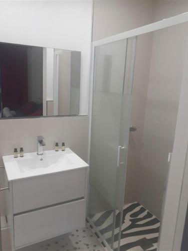 une salle de bain blanche avec un lavabo et une douche dans l'établissement Love Room Sensuelle, à Tremblay-en-France