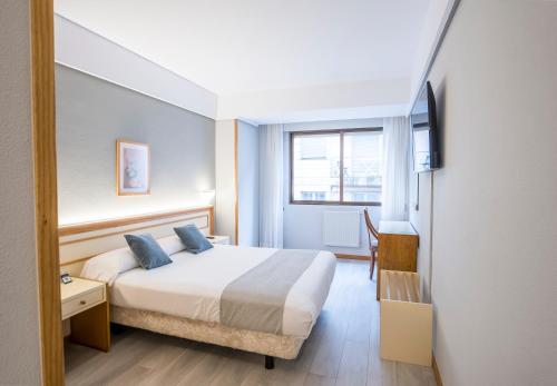 a hotel room with a bed and a window at Hotel Alda Boiro in Boiro
